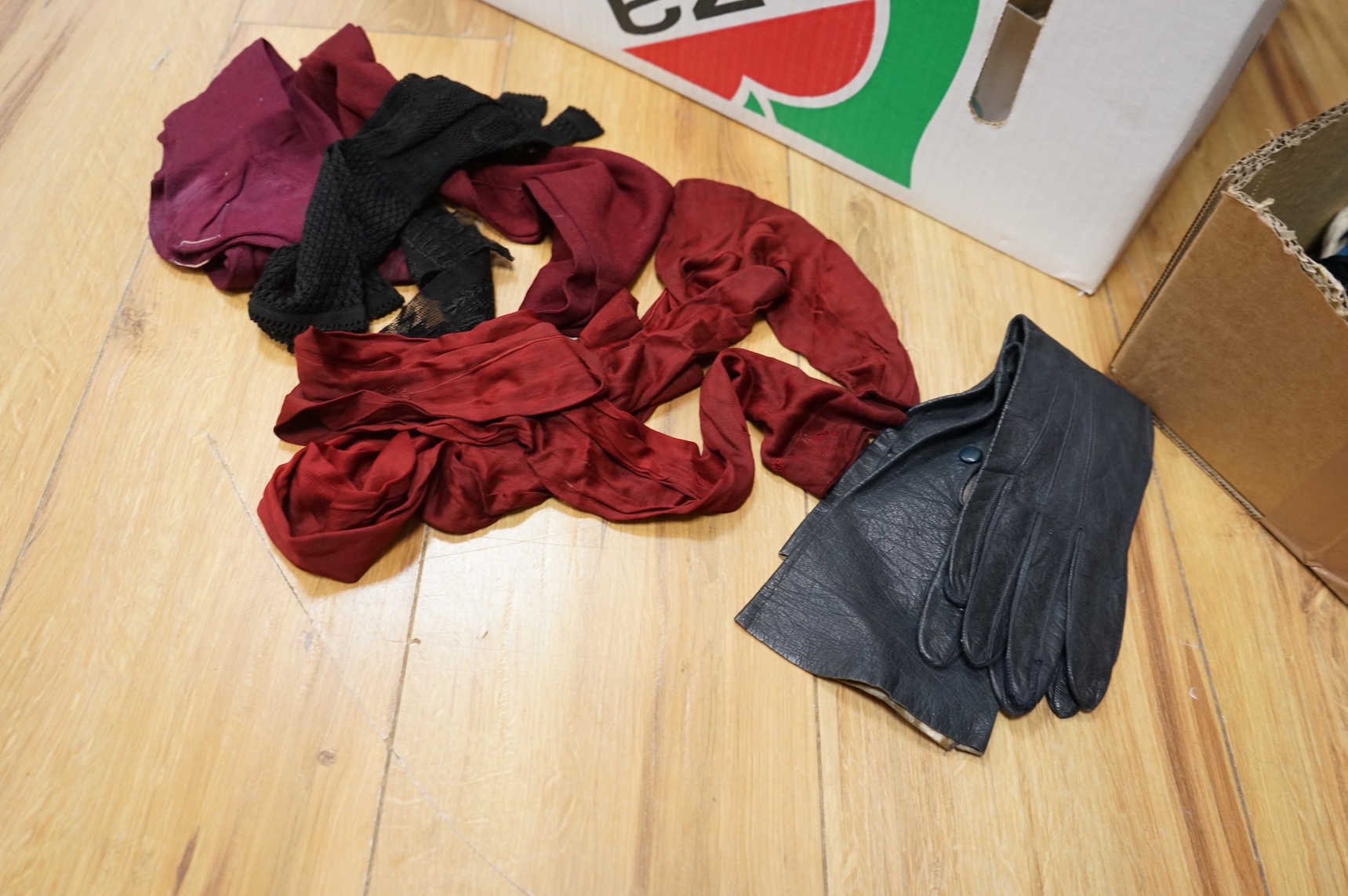 A collection of ladies early 20th century coloured silk stockings, leather and suede belts, a pair of cream leather gauntlets and various gloves